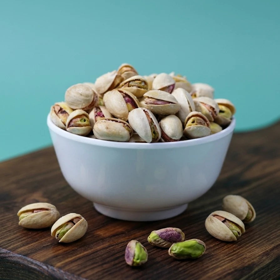 Yathrib salted pistachios in a clear bowl, showcasing green and beige pistachio kernels salted and ready to enjoy.