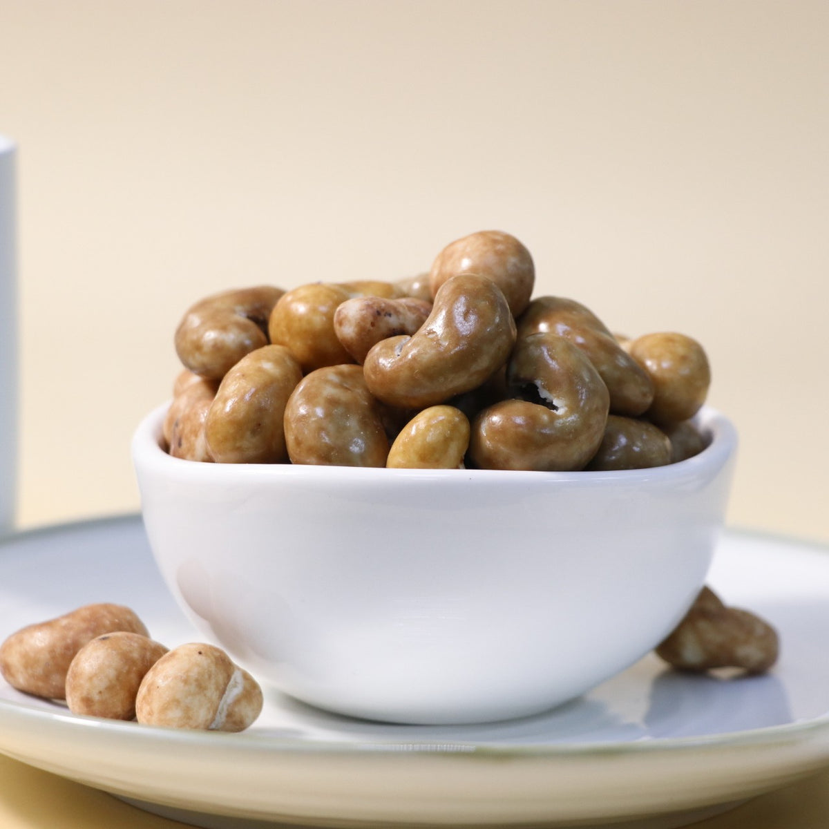 Yathrib Gourmet Caramel Cashew Dragee showing shiny caramel-coated cashews arranged on a white surface.