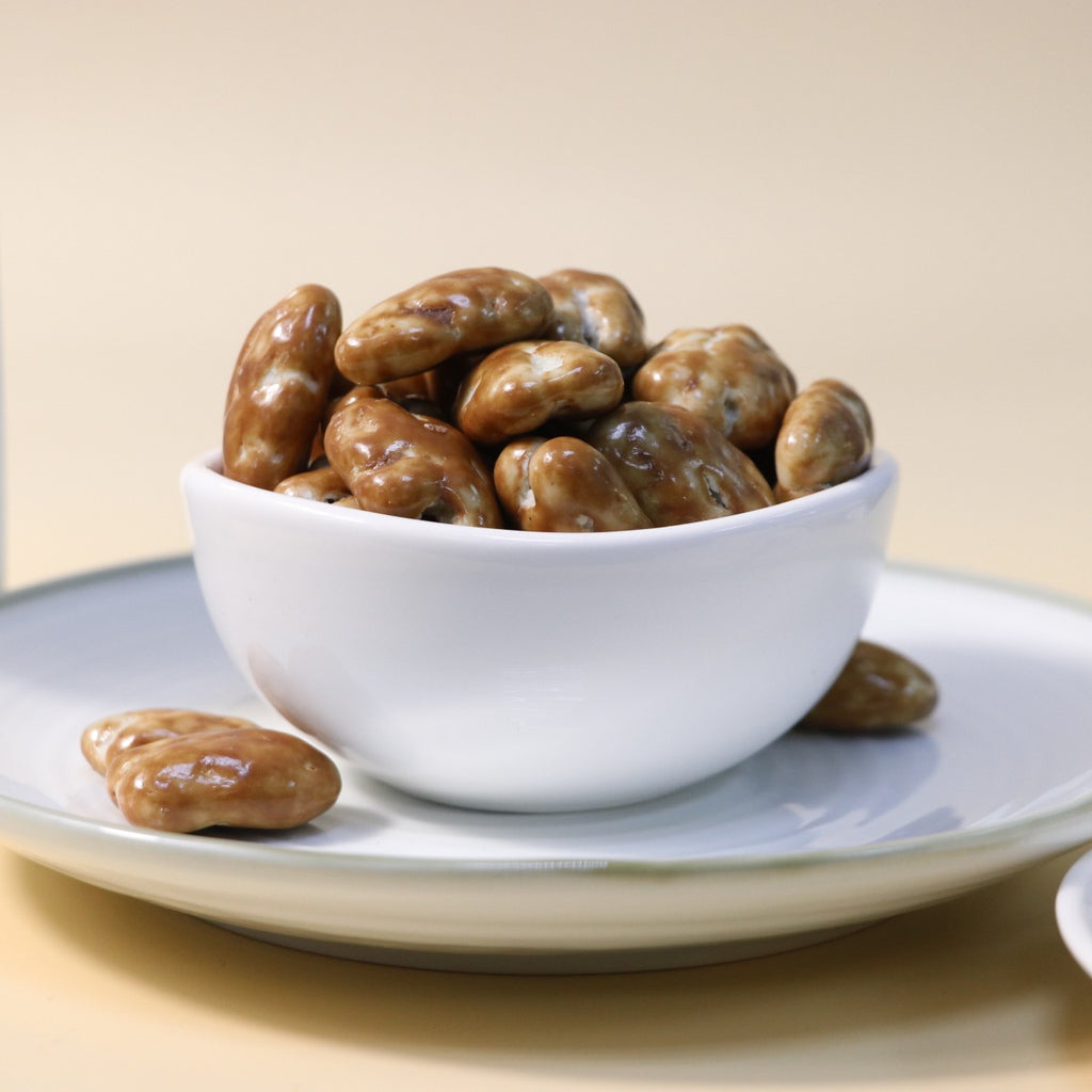 Yathrib caramel pecan dragee with glossy caramel coating and crunchy pecans in a close-up shot.