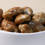Yathrib Caramel Pecan Dragee close-up showing glossy caramel coating over crunchy pecans in a clear container