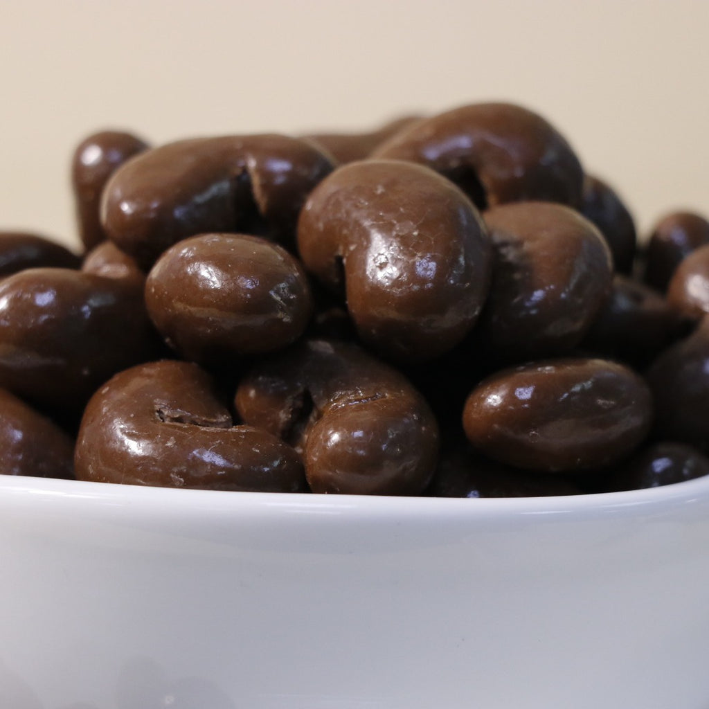 Yathrib Classic Chocolate Cashew Dragee showing glossy chocolate-coated cashews in a clear container.