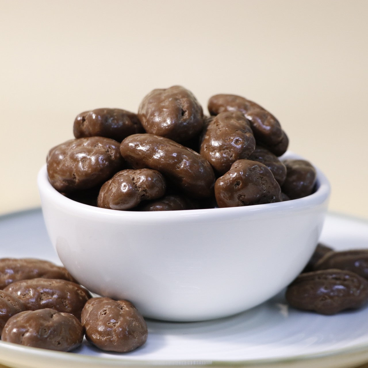 Yathrib Rich Chocolate Pecan Dragee showing glossy chocolate-coated pecans in a clear bowl on a white background.