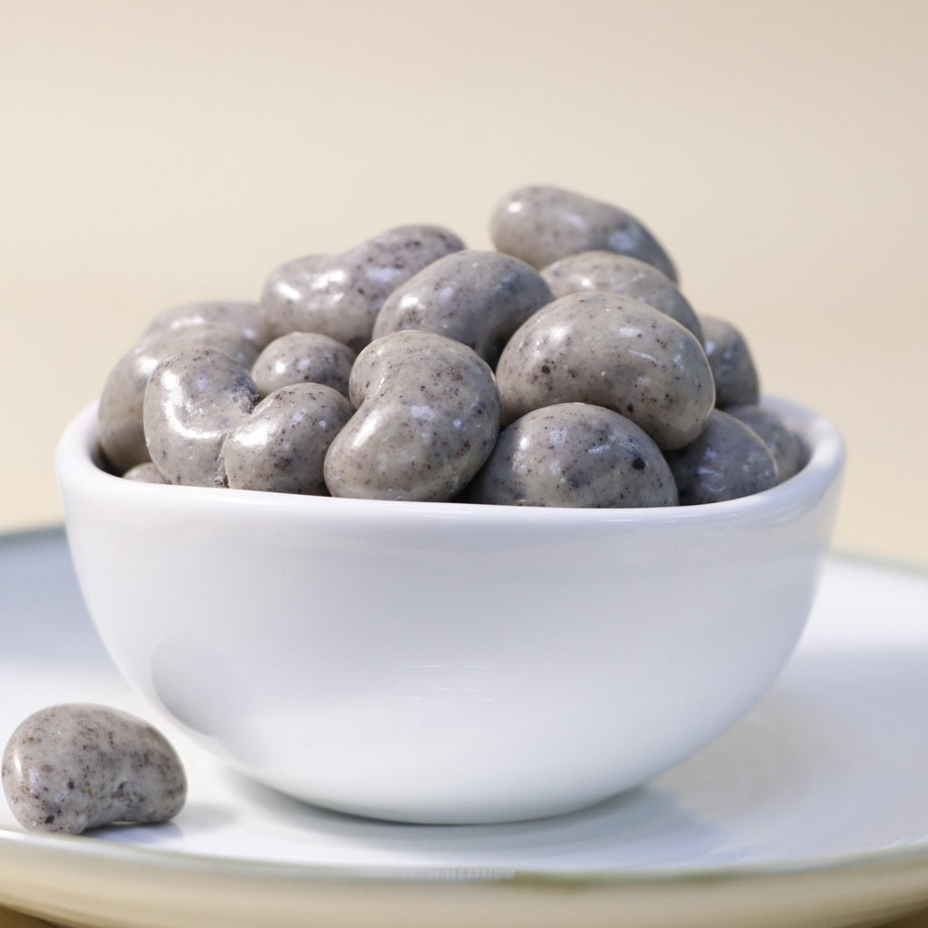 Creamy chocolate cashew dragee by Yathrib, close-up of glossy chocolate-covered cashew candies in a clear container.