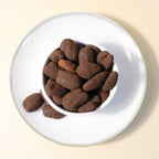 Dark chocolate pecan dragee by Yathrib, featuring glossy chocolate-coated pecans on a white background.