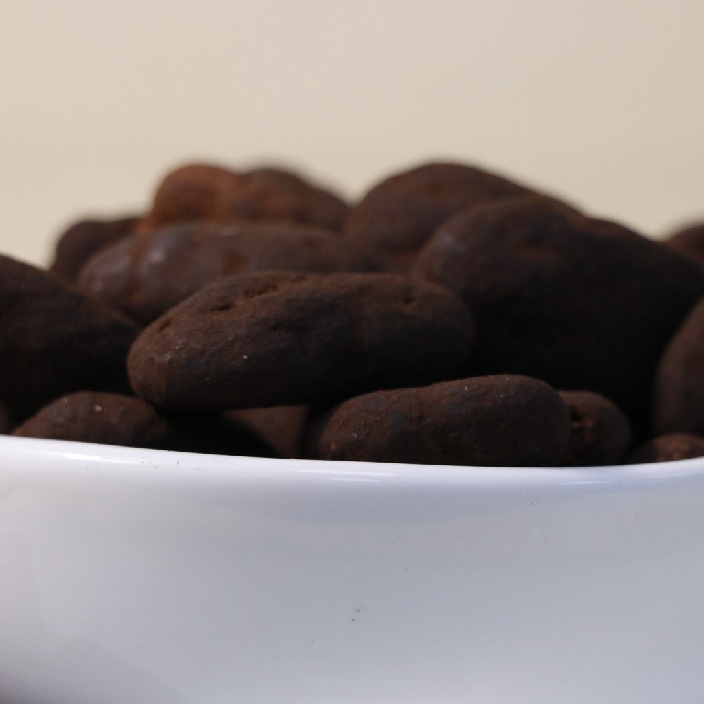 Yathrib dark chocolate pecan dragee showing glossy chocolate coating and crunchy pecans on a white background.