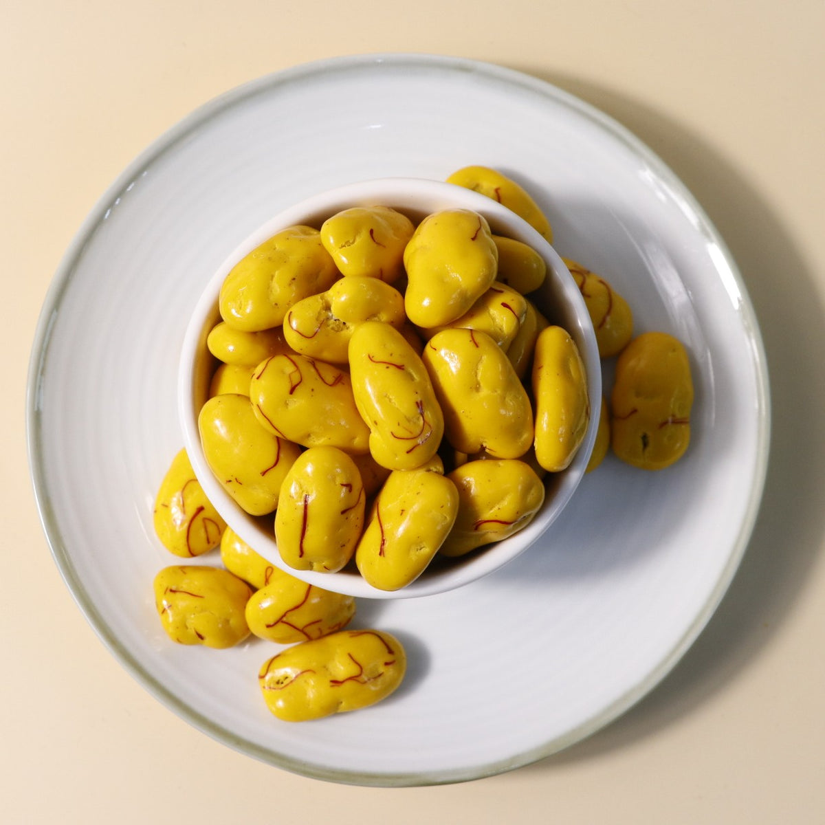 Yathrib Saffron Pecan Dragee close-up showing golden saffron-flavored pecan candies in a clear container.