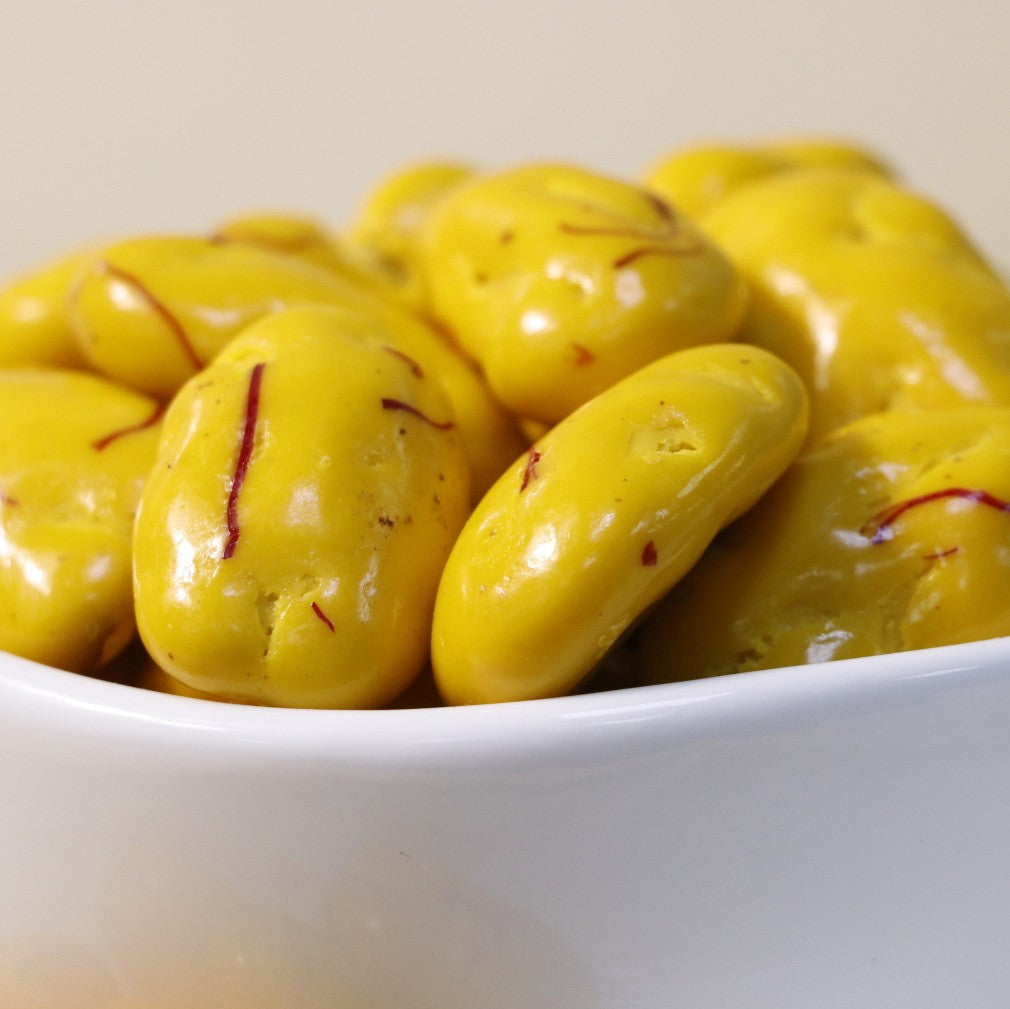 Yathrib Saffron Pecan Dragee with golden saffron and crunchy pecans in glossy coating, presented in a close-up shot.