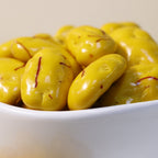 Yathrib Saffron Pecan Dragee with golden saffron and crunchy pecans in glossy coating, presented in a close-up shot.