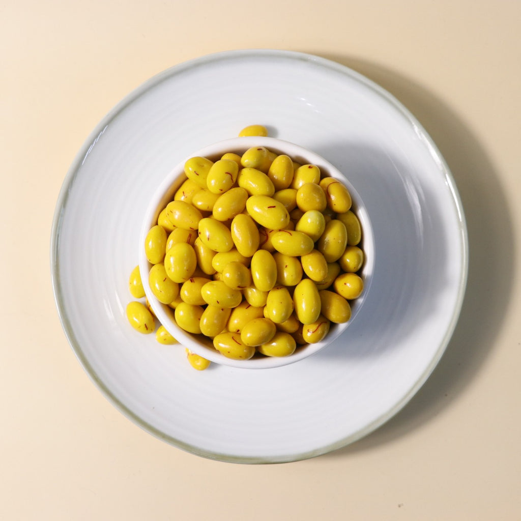 Yathrib saffron pistachio dragee with coated nuts and saffron strands, showcasing a colorful, shiny confection.
