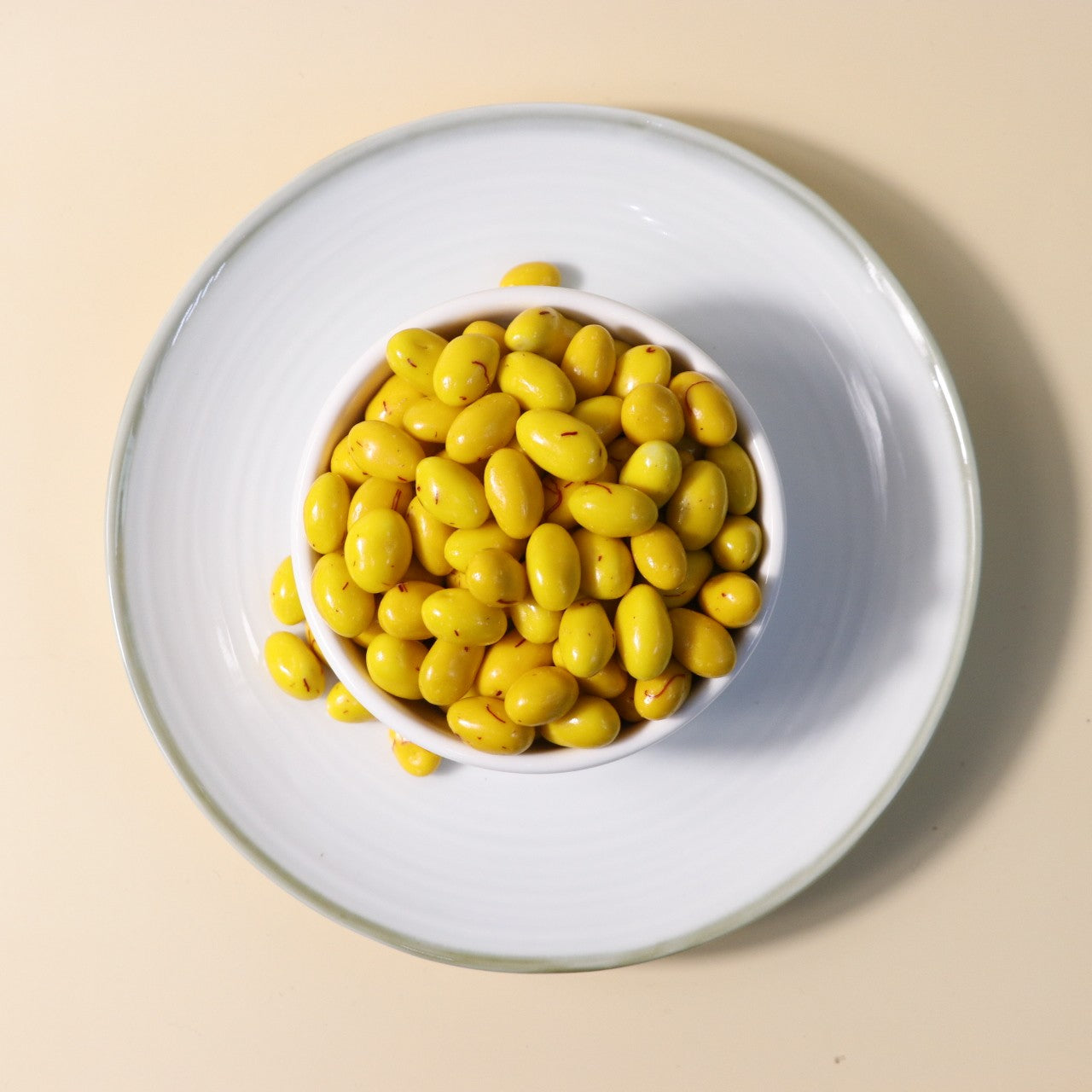 Yathrib saffron pistachio dragee with coated nuts and saffron strands, showcasing a colorful, shiny confection.
