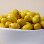Yathrib saffron pistachio dragee showing glossy, golden-coated confections with visible pistachio pieces and saffron accents.