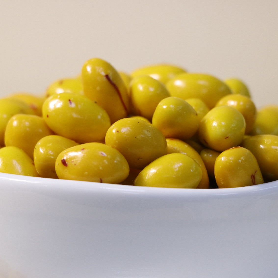 Yathrib saffron pistachio dragee showing glossy, golden-coated confections with visible pistachio pieces and saffron accents.