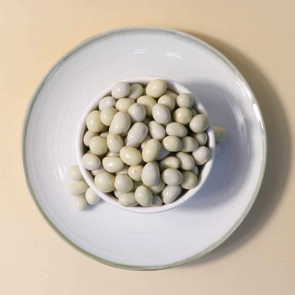 Yathrib White Chocolate Pistachio Dragee showing white chocolate coating with pistachio filling on a white background.
