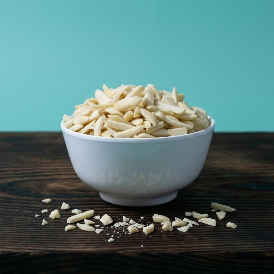 Sliced slivered almonds from Yathrib displayed in a clear bowl on a neutral background.